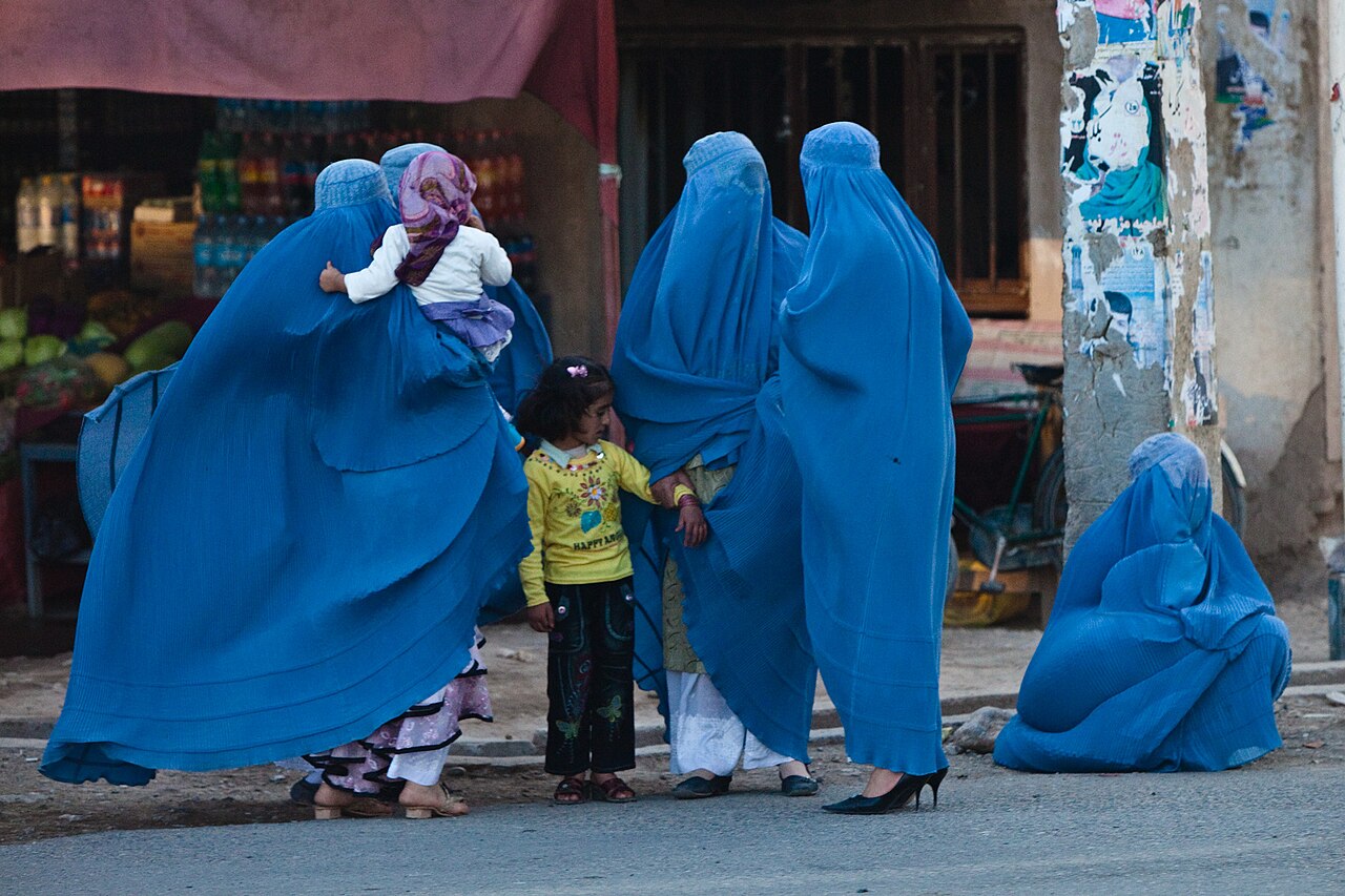 Women in burqas waiting in a street in Herat